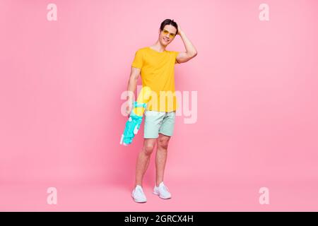 In voller Länge Foto von jungen Kerl glücklich positive Lächeln halten Wasserpistole Splash Sommerurlaub isoliert über Pastellfarben Hintergrund Stockfoto