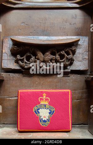 Rotes Kreuz Genähtes Kissen, das die britische Legion mit Einem geschnitzten hölzernen Mercy Seat oder Mönchssitz aus Misericorden darstellt, Christchurch Priory, Großbritannien Stockfoto