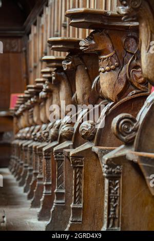 Reihe von geschnitzten hölzernen Mönchssitzen, Mercy Sitze Teil der misericordes im Großen Quire, Christchurch Priorat, Großbritannien Stockfoto