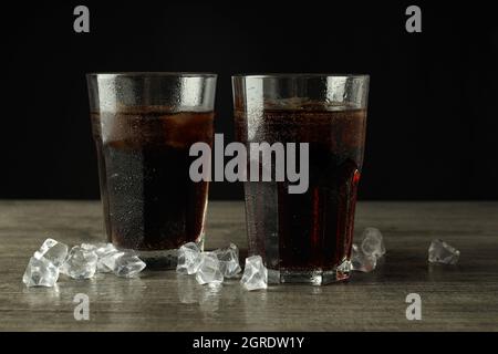 Glas Cola und Eis auf einem grauen Tisch mit Struktur. Stockfoto