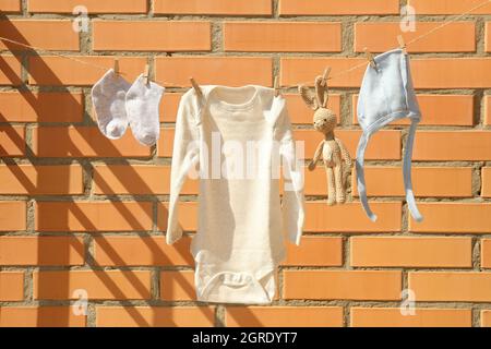 Kinderkleidung an einer Wäscheleine gegen eine Ziegelwand. Stockfoto