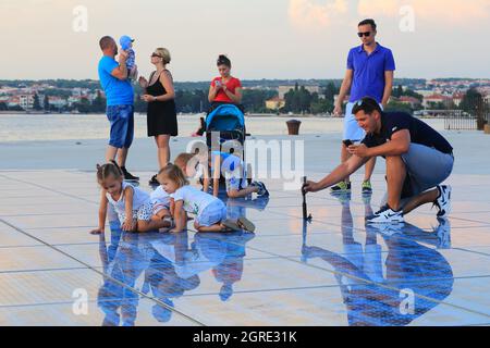 ZADAR, KROATIEN - 14. SEPTEMBER 2016: Nicht identifizierte Familien werden auf einer leuchtenden Installation Greetings to the Sun von ihren Kindern fotografiert Stockfoto