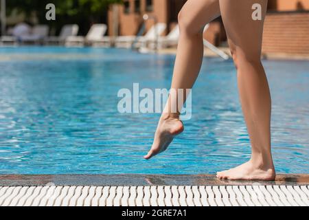 Verkürzte Ansicht einer jungen Frau, die draußen am Pool steht Stockfoto