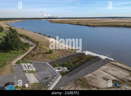 01. Oktober 2021, Brandenburg, Cottbus: Die ehemalige Braunkohlebergwerk Cottbus-Nord füllt sich langsam mit Wasser und wird so zur Cottbuser Ostsee (Luftaufnahme mit Drohne). Die Landmasse rechts auf dem Foto wird in den nächsten Jahren ebenfalls im Wasser verschwinden. Mitte April 2019 begann die Überschwemmung der ehemaligen Tagebaumine Cottbus-Nord. Das Energieunternehmen Lausitz Energie Bergbau AG (LEAG) lässt für das Hochwasser Wasser aus der Spree über den Hammergraben in das Tagebauloch fließen - rund 45 Millionen Kubikmeter pro Jahr sind geplant. Der riesige künstliche See ist Stockfoto