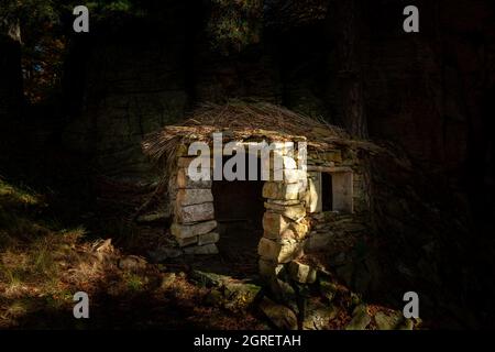 Kleine Steinhütte mitten im Wald, sonniger Herbsttag Stockfoto