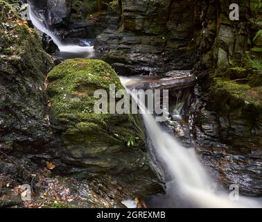 Langzeitbelichtung eines Wasserfalls im Puck's Glen im Argyll Forest Park, Schottland. Stockfoto