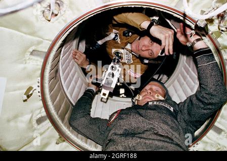 (17-19. Juli 1975) --- Astronaut Thomas P. Stafford und Kosmonaut Aleksei A. Leonov werden während der gemeinsamen Andockmission des Apollo Sojus Test Project (ASTP) in der Erdorbit auf dem Schlupfweg vom Apollo-Andockmodul (DM) zum Sojus-Orbital-Modul (OM) der USA und der UdSSR gesehen. Kosmonaut Leonov ist im OM und Astronaut Stafford im DM. Leonov hält eine Kamera. Stockfoto