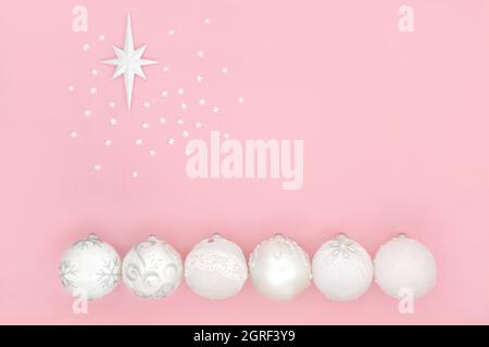 Weiße Weihnachtskugel mit Bethlehem-Sternsymbol und Schneeflocken auf rosa Hintergrund. Minimale abstrakte Komposition für die Weihnachtszeit. Stockfoto