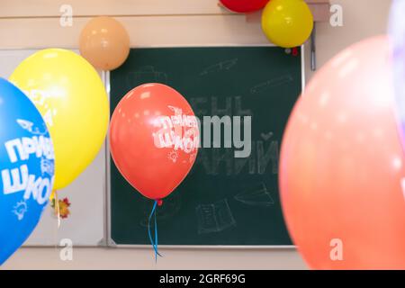 Schulklasse am 1. September ohne Schüler mit bunten Ballons auf dem Hintergrund des Schulrates. Die Inschriften sind Tag des Wissens und Hölle Stockfoto