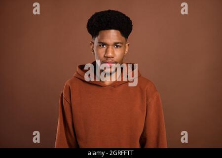 Foto von ruhig fokussierten seriöse gut aussehende afrikanische guy Look Kamera tragen Kapuzenpullover auf braunem Hintergrund isoliert Stockfoto