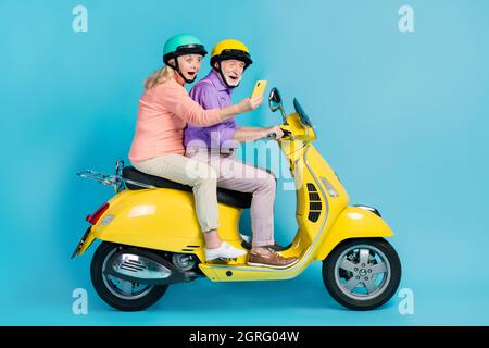 In voller Größe Profil Seite Foto von verrückten Ruhestand grauhaarige Rentner Paar Fahrt Helm schauen Handy-Karte isoliert auf blauem Hintergrund Stockfoto