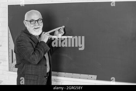 Älterer Mann Lehrer verwenden Kompass Werkzeug. Bärtiger Lehrer Mann zeichnen mit Kompass auf Tafel. Zurück zur Schule. Konzept für mathematische Grafikwerkzeuge. Zu wissen Stockfoto