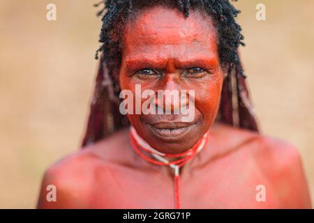 Indonesien, Papua, Stadt Wamena, Porträt einer jungen Dani-Frau, bedeckt mit roter Erde. Baliem Valley Cultural Festival, jedes Jahr im August kommen Stämme zusammen, um uralte Kriegsszenen aufzuführen, Parade und Tanz in traditioneller Kleidung Stockfoto