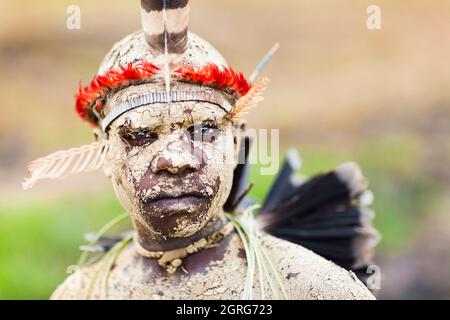 Indonesien, Papua, Stadt Wamena, Porträt eines jungen Dani-Jungen, Gesicht und Körper aus Erde. Baliem Valley Cultural Festival, jedes Jahr im August kommen Stämme zusammen, um uralte Kriegsszenen aufzuführen, Parade und Tanz in traditioneller Kleidung Stockfoto