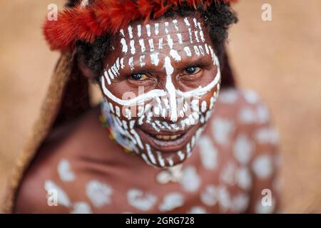 Indonesien, Papua, Stadt Wamena, Porträt einer jungen Dani-Frau, die weißes Make-up auf Gesicht und Körper trägt. Baliem Valley Cultural Festival, jedes Jahr im August kommen Stämme zusammen, um uralte Kriegsszenen aufzuführen, Parade und Tanz in traditioneller Kleidung Stockfoto