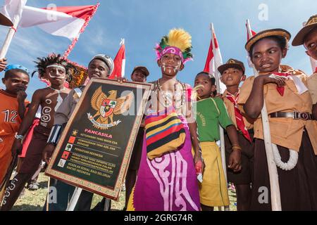 Indonesien, Papua, Innenstadt von Wamena, Kinderparade, Feier des indonesischen Unabhängigkeitstages. Jeder Stamm ist eingeladen, seine Kultur durch Tänze und traditionelle Kleidung zu präsentieren, um das Gefühl kultureller Freiheit zu stärken. Das Zeichen zeigt das nationale embleme Indonesiens und sein Motto: Einheit in Vielfalt. Stockfoto