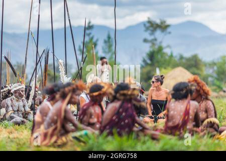 Indonesien, Papua, Stadt Wamena, junge westliche Touristen, die unter Frauen des Dani-Stammes posiert. Baliem Valley Cultural Festival, jedes Jahr im August kommen Stämme zusammen, um uralte Kriegsszenen aufzuführen, Parade und Tanz in traditioneller Kleidung Stockfoto