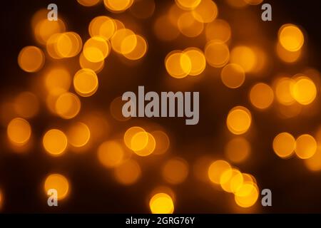Abstrakter Hintergrund, orangefarbenes Bokeh auf schwarzem Hintergrund, festlicher Hintergrund. Stockfoto