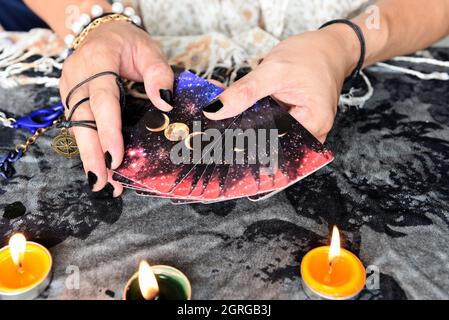 Zeig Wahrsagern von Händen, die Tarot-Karten halten und Tarot-Leser mit Kerzenlicht auf dem Tisch, Lesungen, magische Darbietungen, Dinge, die mein sind Stockfoto