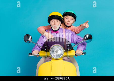 Foto des Rentners Ehemann Frau Fahrt Motorrad Point Finger stauned schockiert isoliert auf blauem Hintergrund Stockfoto