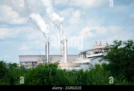 Aus einem riesigen, weißen Rauch, der aus Rauchgassen oder Abluftrohren in den Fabrikschornsteinen kommt, kommt dichter und starker Rauch, der Wasserdampf abgibt, der konisch ist Stockfoto