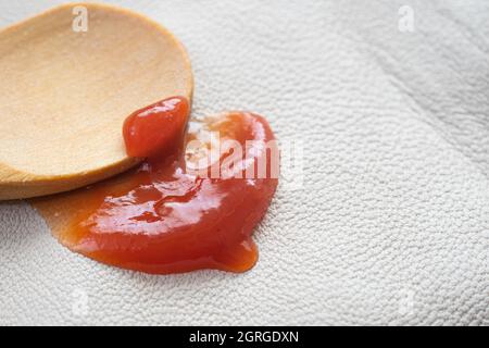 Ketchup-Fleck auf weißer Lederstruktur, Makro-Textur, Reinigungskonzept Stockfoto