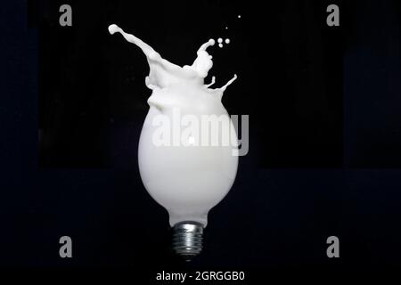 Milchspritzer in einer Glühbirne, isoliert auf Schwarz Stockfoto