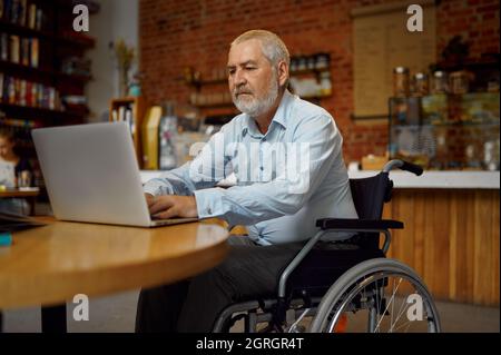 Behinderter Mann im Rollstuhl mit Laptop Stockfoto
