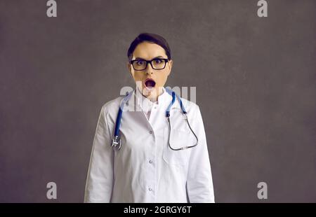 Studioportrait einer lustig schockierten Krankenschwester oder eines Arztes mit offenem Mund und Blick auf die Kamera Stockfoto