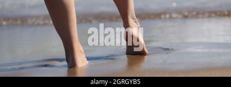 Frau geht auf See, ein Teil des Körpers genießt die Zeit am Strand Stockfoto