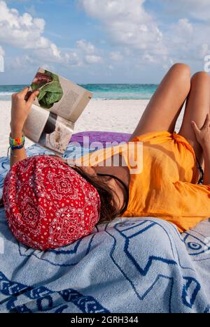 Eine nicht erkennbare junge Frau liest ein Buch an einem tropischen Strand in Tulum, Mexiko. Stockfoto