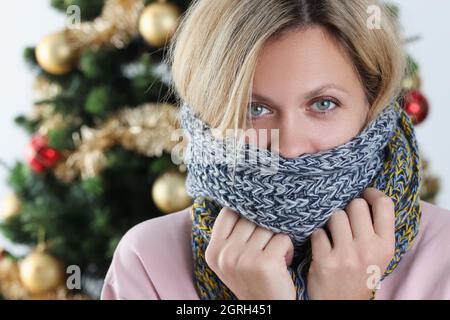 Porträt einer jungen Frau in Schal auf dem Hintergrund des Weihnachtsbaums gewickelt Stockfoto