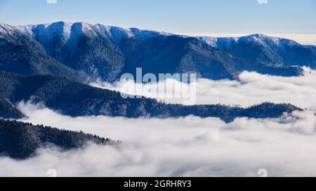 Wolkenmeer in den Bergen, das durch Temperaturumkehr entsteht. Blick in die Bucegi-Berge (Teil der Karpaten), Rumänien. Schichten, Winter Stockfoto