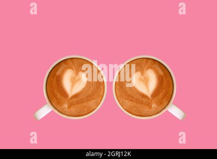 Ein Paar herzförmiger Latte Art Cappuccino-Kaffee auf einem Hintergrund in Flamingo Pink Stockfoto