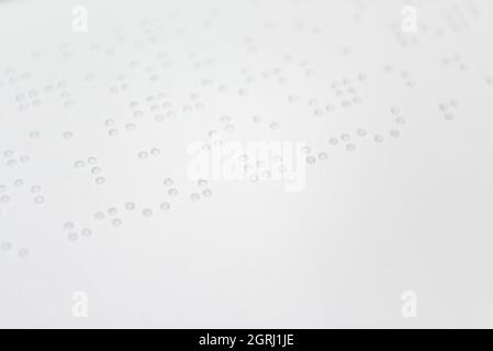 Ein Textfragment in Louis-Braille-Schrift, das mit speziellen Druckgeräten auf ein Standardpapier gedruckt wurde. Stockfoto