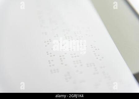 Ein Textfragment in Louis-Braille-Schrift, das mit speziellen Druckgeräten auf ein Standardpapier gedruckt wurde. Stockfoto