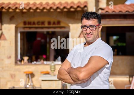 Porträt eines positiv selbstbewussten Mannes mittleren Alters, der eine Brille mit gekreuzten Armen trägt Stockfoto