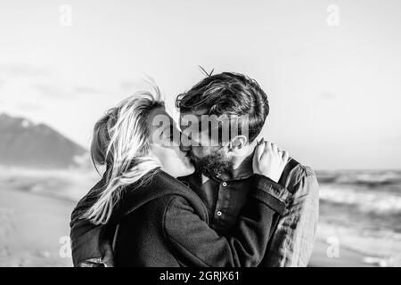 Romantisches Hipster-Paar in der Liebe küssen am Ufer am wilden Strand - Freund und Freundin tragen coole Kleidung und Vintage-Rucksack küssen ich Stockfoto