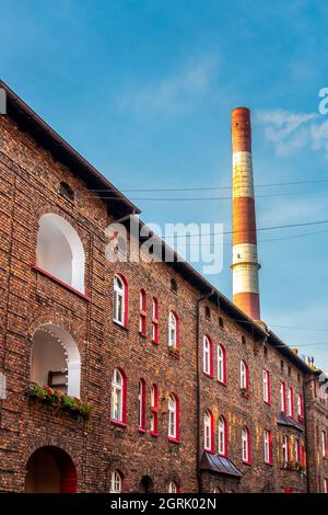 Fassade des Gebäudes in einem traditionellen, schlesischen Bezirk Nikiszowiec in Katowice, Polen. Alte Backsteinhäuser mit rot gestrichenen Fensterrahmen. Werk Stockfoto