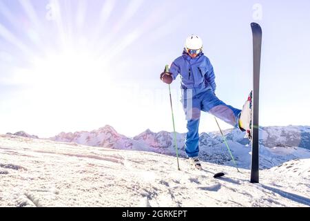 Junger Skifahrer auf blauer Uniform bei Sonnenuntergang im Relax Moment im skigebiet der französischen alpen - Winterabenteuer und Sportkonzept mit Profi-Mann am Berg Stockfoto