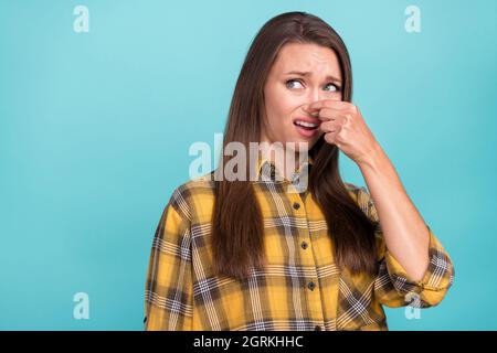 Foto von irgenten jungen Mädchen Arm Finger halten Abdeckung Nase suchen leeren Raum auf blauem Hintergrund isoliert Stockfoto