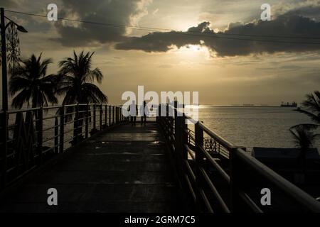 Zwei Personen überqueren den Roxas Boulevard auf einer Fußgängerbrücke in Richtung Baywalk in Manila, Philippinen Stockfoto