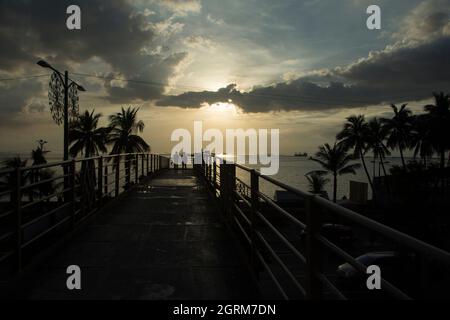 Zwei Personen überqueren den Roxas Boulevard auf einer Fußgängerbrücke in Richtung Baywalk in Manila, Philippinen Stockfoto