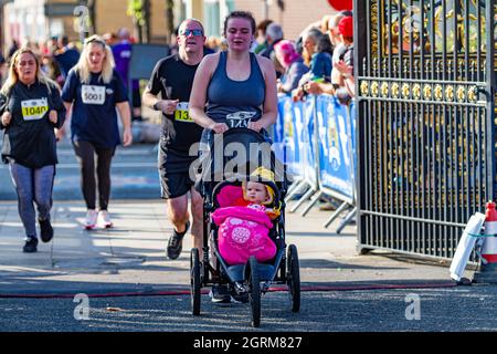 Warrington Running Festival 2021 - Frau schiebt ihre kleine Tochter über die Ziellinie Stockfoto