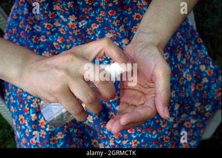 Lady desinfiziert ihre Hände mit Spray Stockfoto
