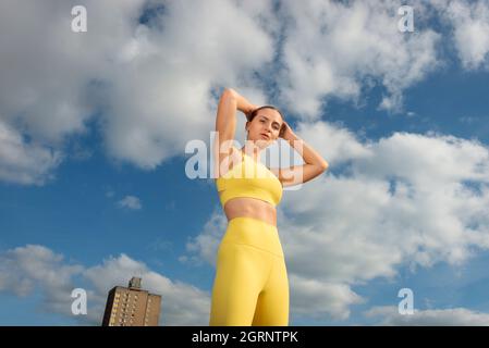 Sportliche und fit junge Sportlerin mit blauem Himmel Hintergrund. Das Konzept eines gesunden Lebensstils und Sports. Stockfoto