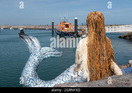 Meerjungfrau mit Blick auf das Rettungsboot, das im Brixham Harbour in South Devon England festgemacht ist Stockfoto