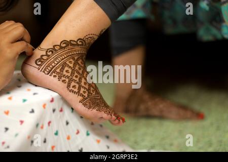 Nahaufnahme der Braut mit Henna an beiden Händen vor dunklem verblasstem Kleid Hintergrund Stockfoto