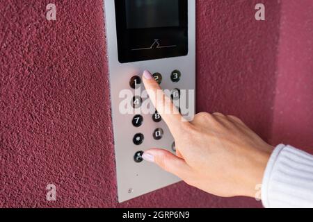 Eine junge Frau wählt den Wohnungscode auf dem Bedienfeld einer elektronischen Gegensprechanlage. Schutz- und Sicherheitskonzept Stockfoto