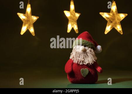 Santa, leuchtende Girlanden und grüner Hintergrund. Festliche Dekorationen für Weihnachten und Neujahr. Stockfoto